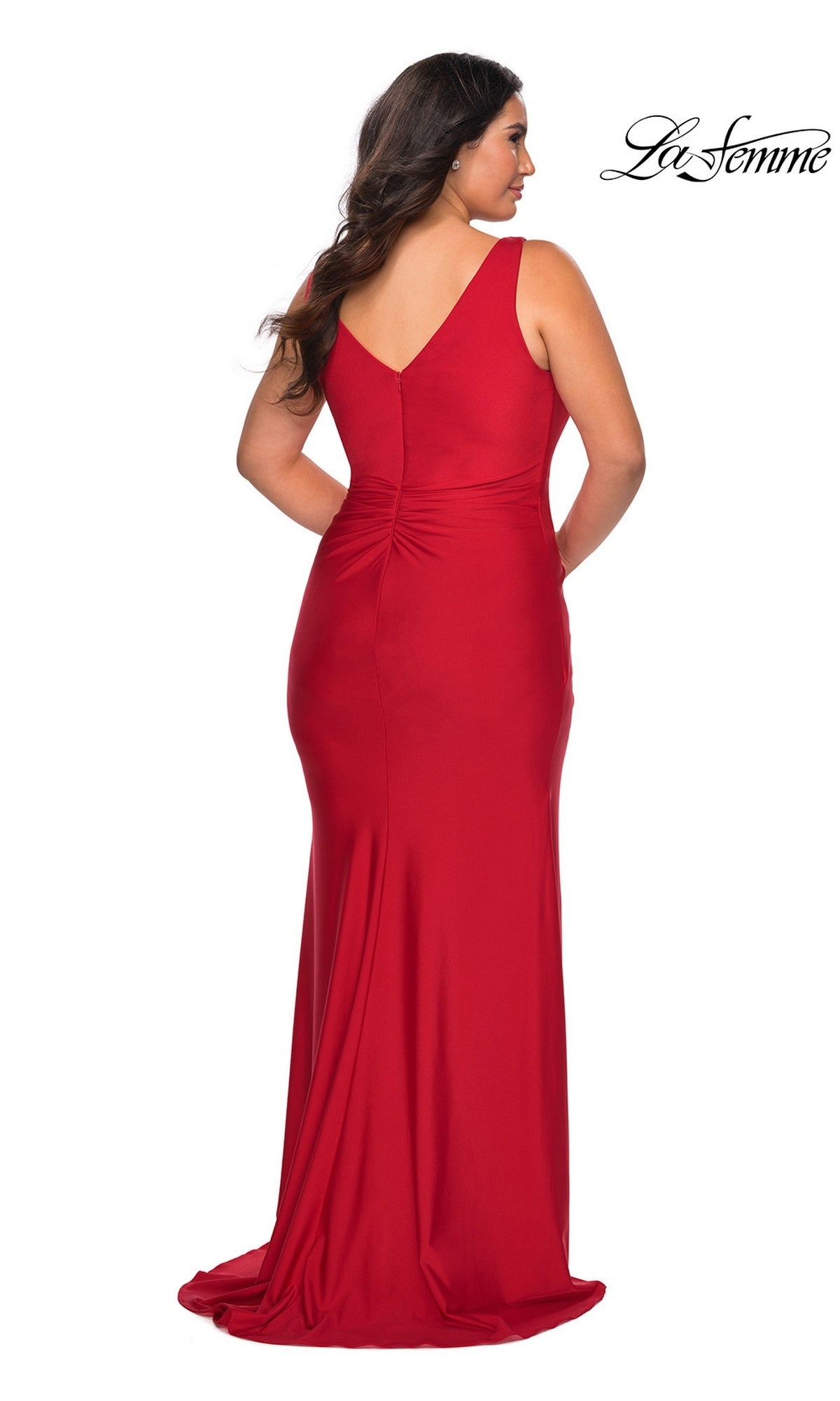 A woman viewed from behind, wearing a Long Plus-Size Prom Dress: La Femme 29024, a sleeveless, floor-length red V-neck gown with a gathered waist.